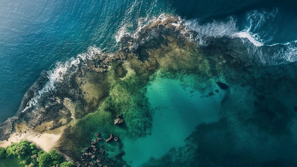 Aerial view of a rocky coastline surrounded by clear blue water
